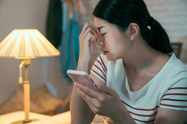 eye-mask-for-dry-eyes Woman with closed eye phone in hand
