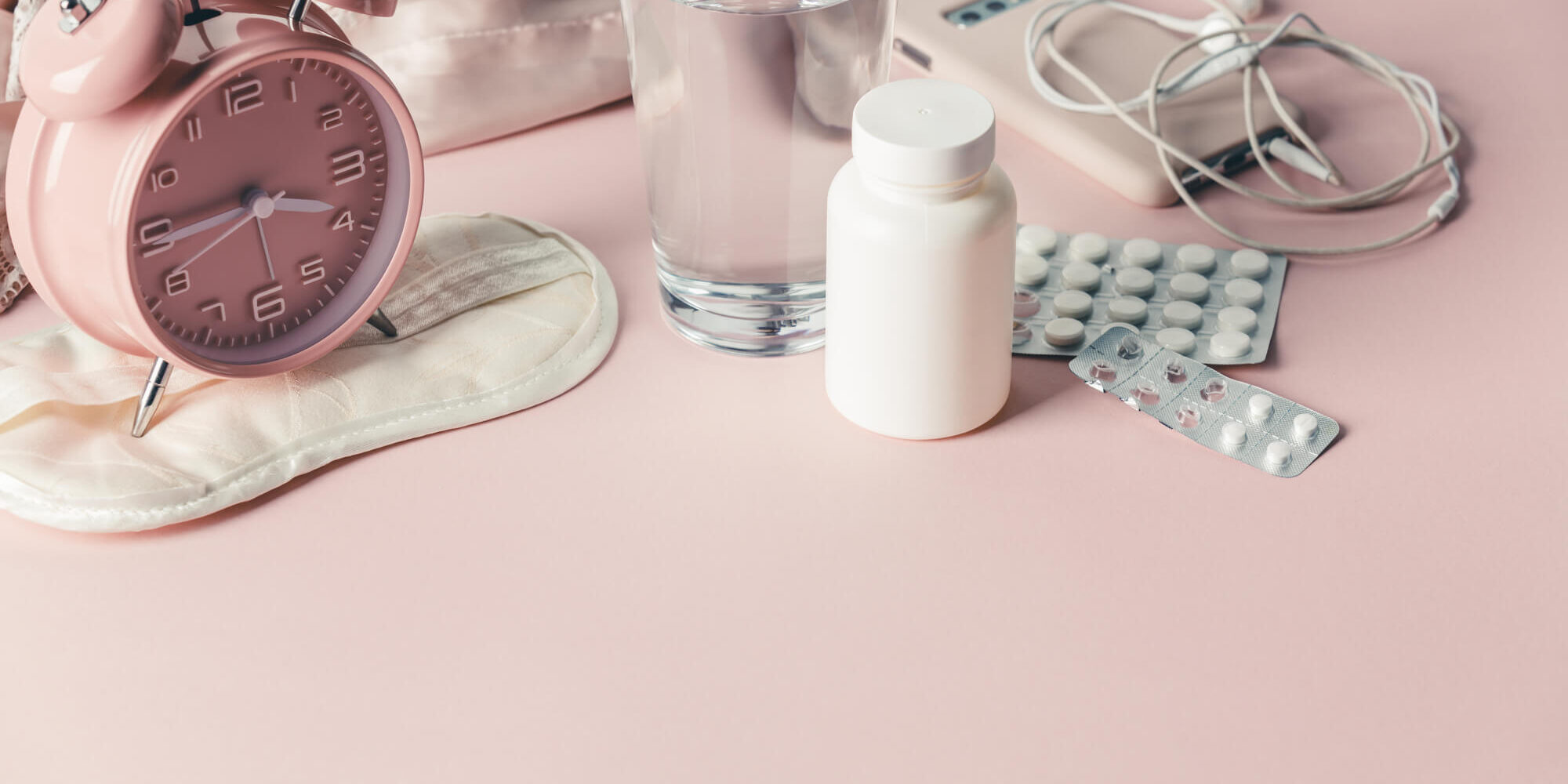 A water glass, Pink alarm watch and tablets in a pink background