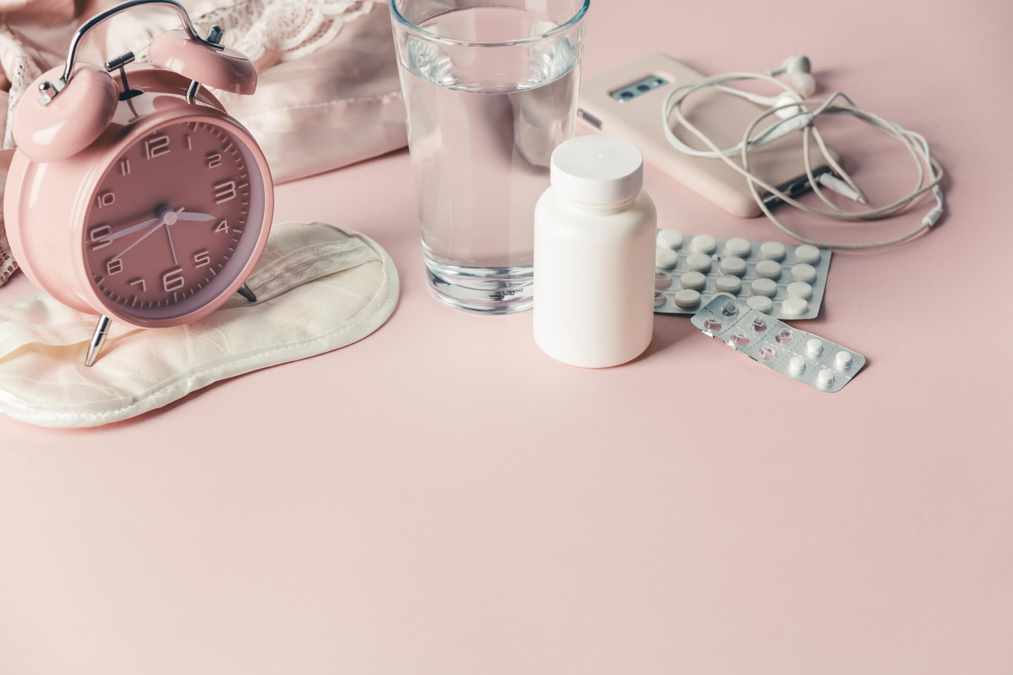A water glass, Pink alarm watch and tablets in a pink background