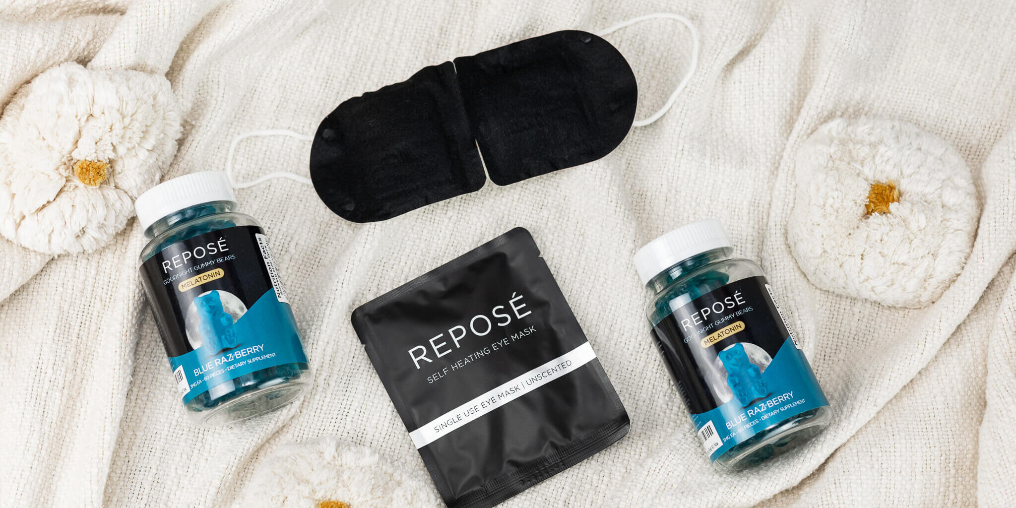 black eye mask, bottle of blue gummy bears on a white cloth