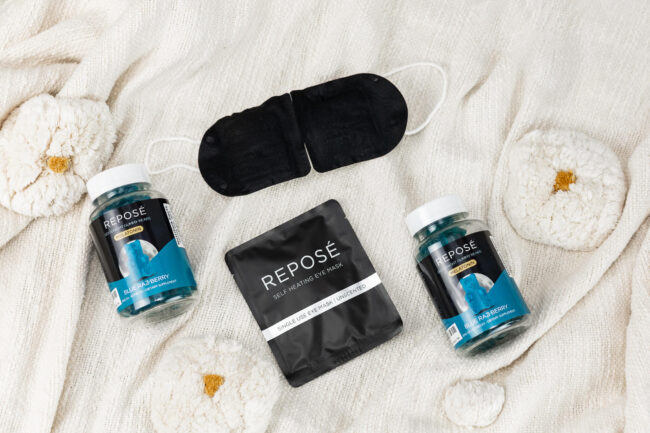 black eye mask, bottle of blue gummy bears on a white cloth