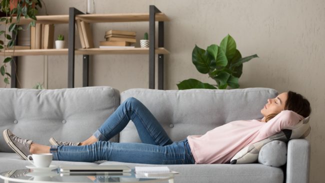 Tired,Young,Woman,Lying,On,Cozy,Couch,Take,Nap,Daydreaming a woman power napping on sofa
