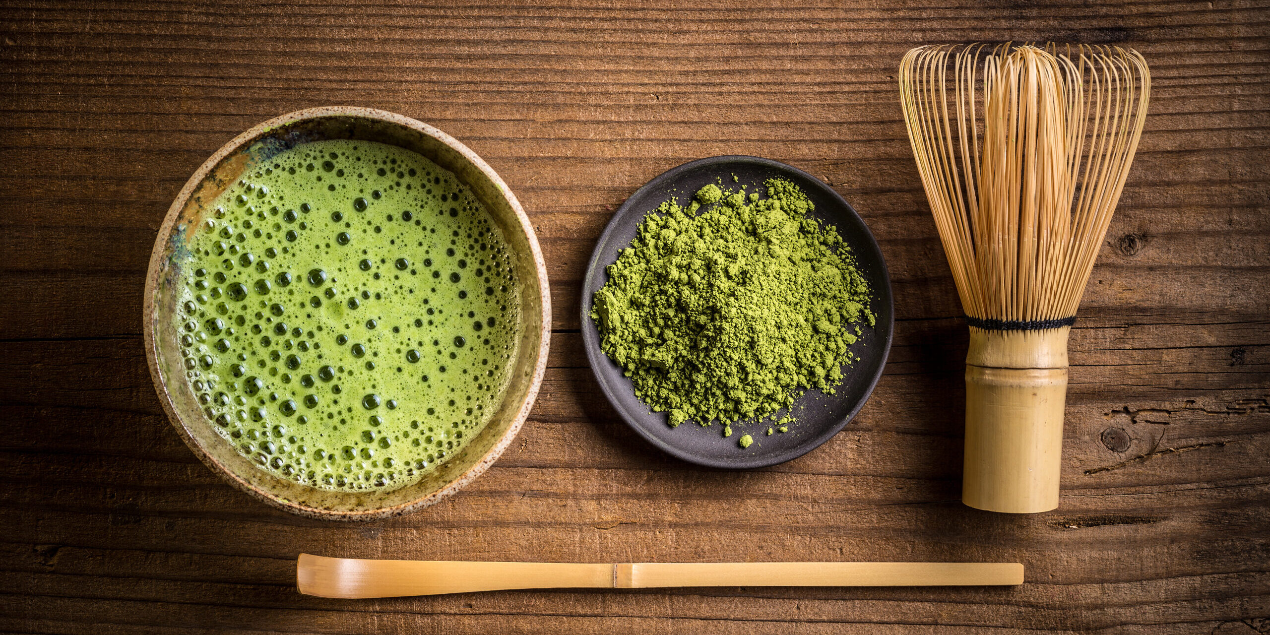 matcha tea in a bowl alongwith matcha power and hand mixer