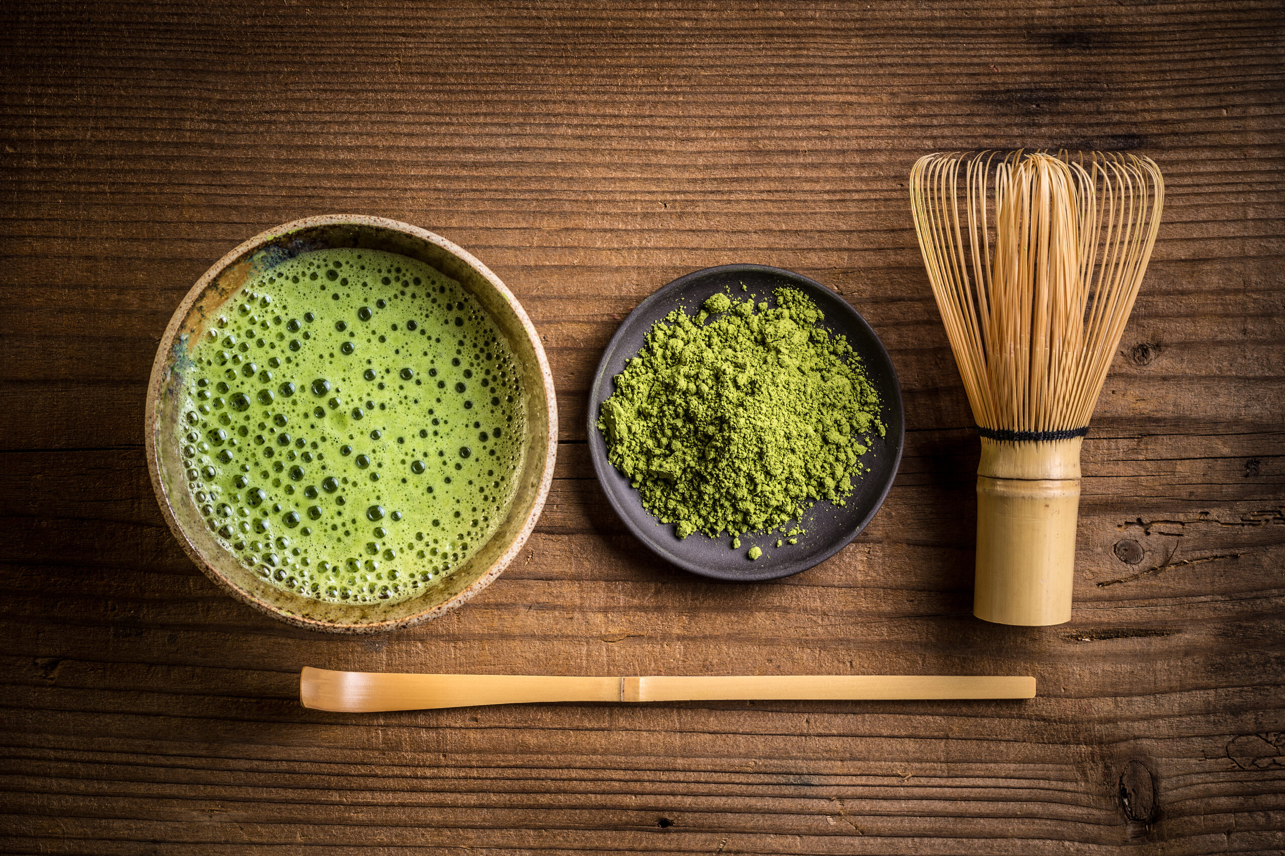 matcha tea in a bowl alongwith matcha power and hand mixer
